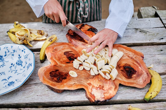 Hands cutting bananas with a knife