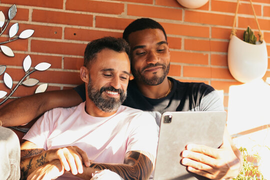 Smiling multiracial gay couple making video call with tablet