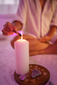 Female burning Palo Santo wood over candle at home