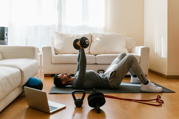 Athlete doing dumbbell exercise during online workout