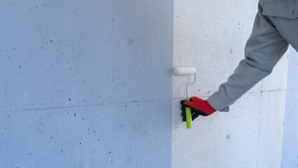 Obraz na płótnie Canvas 外壁塗装のイメージ｜コンクリート壁とペイントローラーを持つ作業員
