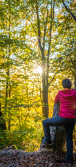 Young woman enjoying the fall colors among beech trees in October.