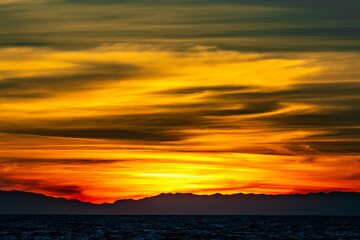 Burning sunset colors of green, yellow, orange and red clouds 