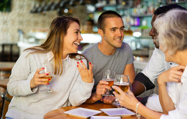 View on the young Latin couple talking to diversse group at a bar..