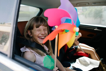 A girl in a car with a windmill toy