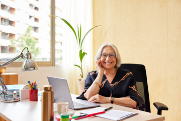 Cheerful senior freelancer sitting at desk