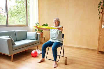 Smiling elderly woman exercising with elastic band