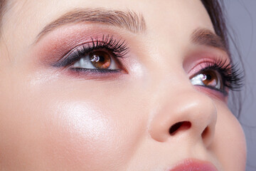 Closeup shot of human woman face. Female with face and eyes beauty makeup with pink smoky eyes eye shadows