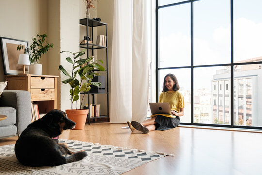 Woman with dog using laptop at home