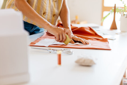 A woman&rsquo;s hands mark a pattern with chalk