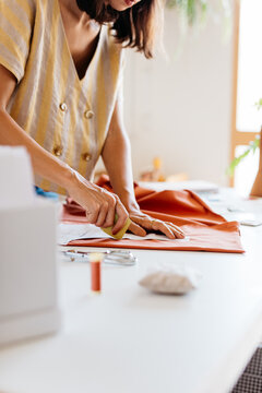 A woman&rsquo;s hands mark a pattern with chalk