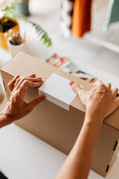 a woman's hands places a label on a package 