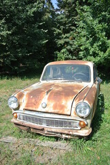 Old soviet rusty car in the forest on a sunny day 
