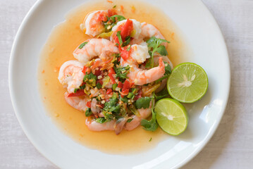 Fresh shrimp on white plate and fresh vegetables, cooked shrimps prawns and seafood spicy chili sauce coriander, cooking shrimp salad lemon lime - top view