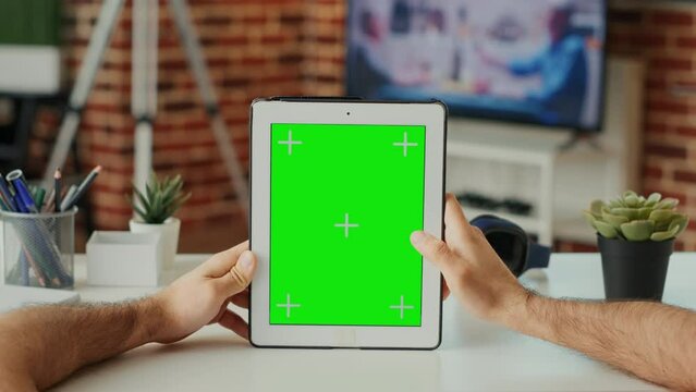 Caucasian manager using digital tablet with greenscreen template, vertically holding wireless device with isolated display. Working with blank chroma key background and mock up screen. Close up.