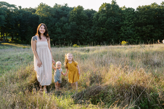 Mother and her children standing in field at sunset