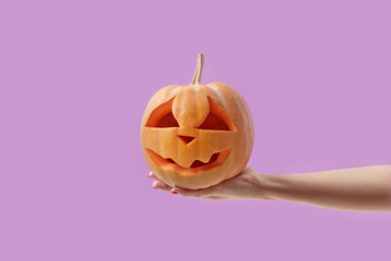 Pumpkin with Halloween carving in female hand.