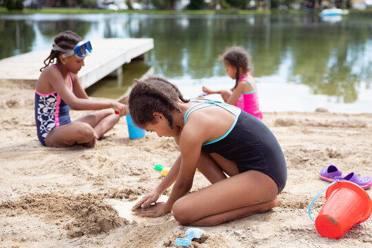 Three children playing on the beach at a lake. 