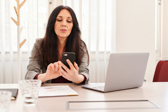 Mature businesswoman texting at work