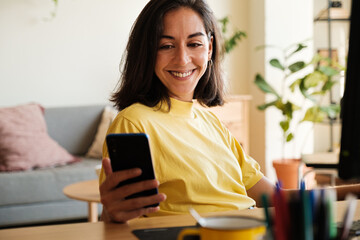 Smiling woman looking phone during work