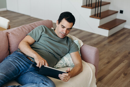 Middle aged male with tablet chilling on couch