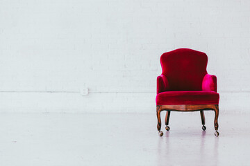 Vintage red velvet wingback chair in a white brick studio