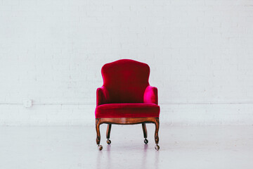 Vintage red velvet wingback chair in a white brick studio
