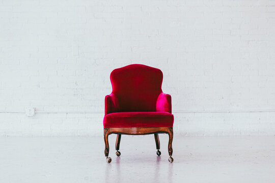 Vintage red velvet wingback chair in a white brick studio