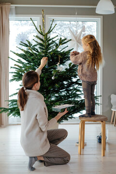 Woman with child decorating Christmas tree