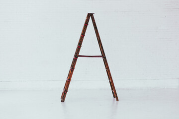Profile view of Antique wooden ladder in modern white brick warehouse