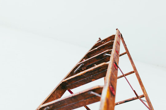 Profile view of Antique wooden ladder in modern white brick warehouse