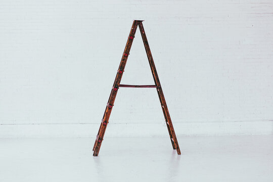 Profile view of Antique wooden ladder in modern white brick warehouse