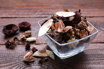 Aromatic potpourri of dried flowers in glass bowl on wooden table