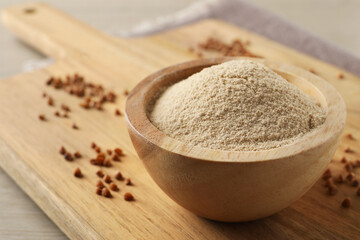 Bowl of buckwheat flour on white wooden table, closeup. Space for text