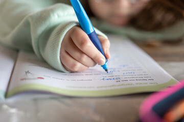 Homework.schoolgirl does her homework. child writes with a pencil in a notebook.Close-up pencil in a childs hand.Study and education