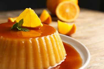 Delicious pudding with caramel, orange and mint on wooden table, closeup - obrazy, fototapety, plakaty