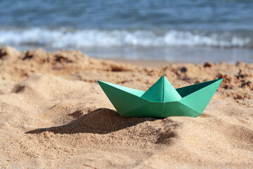 Green paper boat near sea on sunny day, space for text