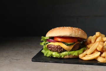 Delicious burger and french fries served on grey table. Space for text