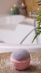 Beautiful bath bomb on wicker mat in bathroom