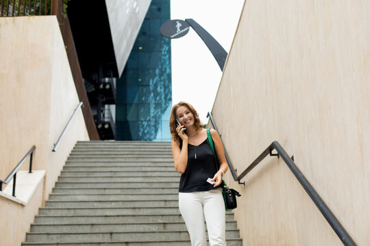 The woman descends into the underpass  and speaks on the phone