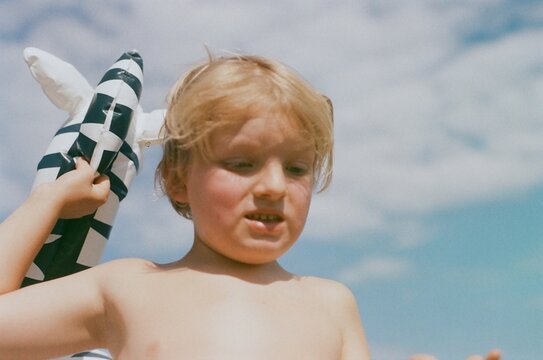 A boy on a beach with a floatable toy zebra 