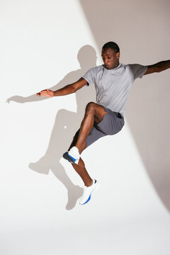 Black sportsman jumping against gray backdrop