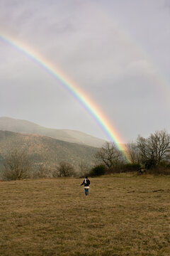 unrecognizable woman running towards a rainbow