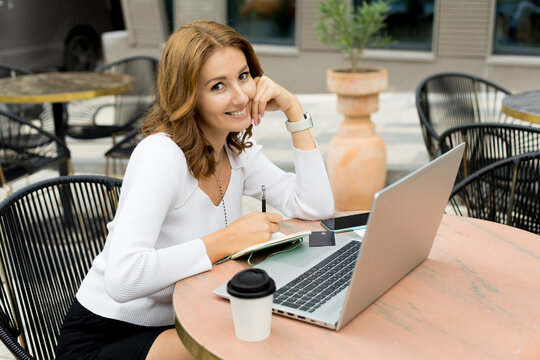 Woman working on laptop on cafe terrace