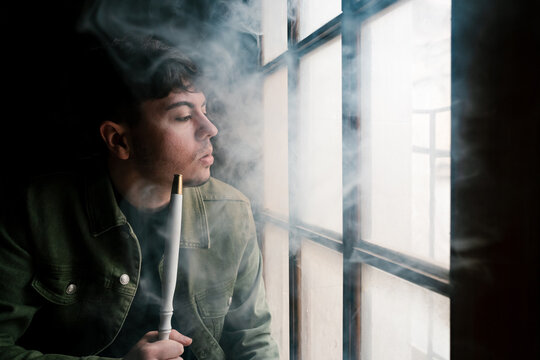 Man with hookah looking out window