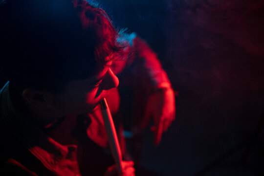 Young brunet smoking hookah in dark room