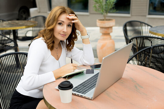 Woman working on laptop on cafe terrace