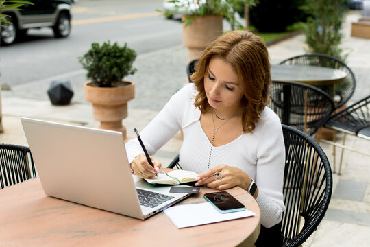 Woman working on laptop on cafe terrace