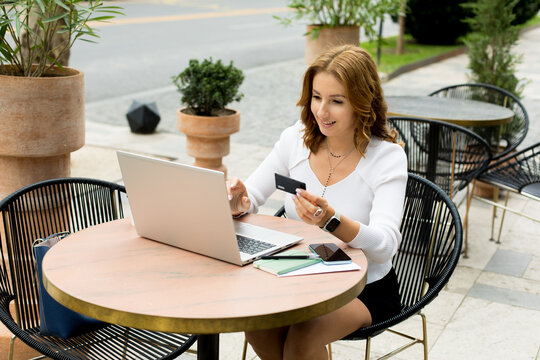 Woman working on laptop on cafe terrace