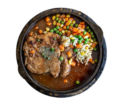 pork stake serve on hot pan with gravy suace with green bean carrot and corn from top view on clear background